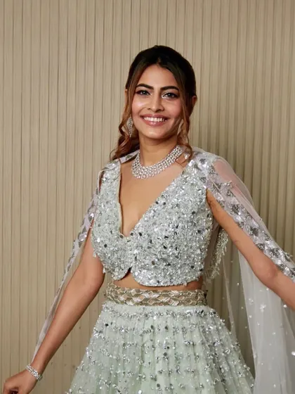 A happy and confident shot of a student's work, showcasing a shimmering silver lehenga look.