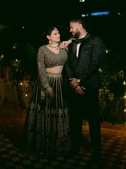 A stylish reception portrait of the couple against a backdrop of fairy lights, looking elegant and happy.