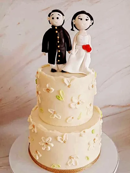 A cute two-tier engagement cake. I handcrafted the couple figurines to resemble the happy pair, making it a sweet and personal centerpiece for their celebration.