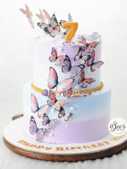 A cascade of delicate wafer paper butterflies seems to fly up this two-tier cake. The soft pastel ombre of purple and blue creates a dreamy backdrop.