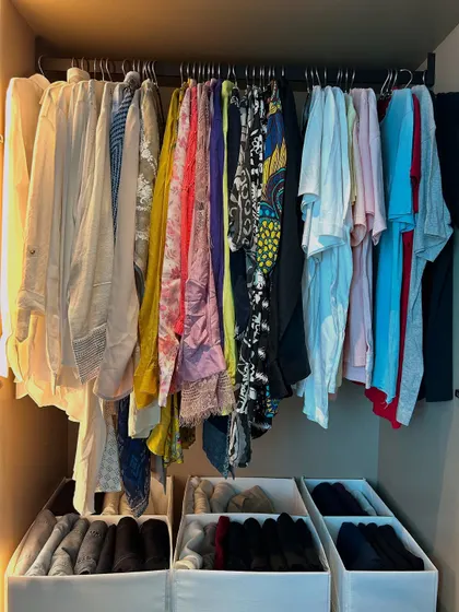 This closet uses bins on the shelves to contain folded items, preventing stacks from becoming messy.