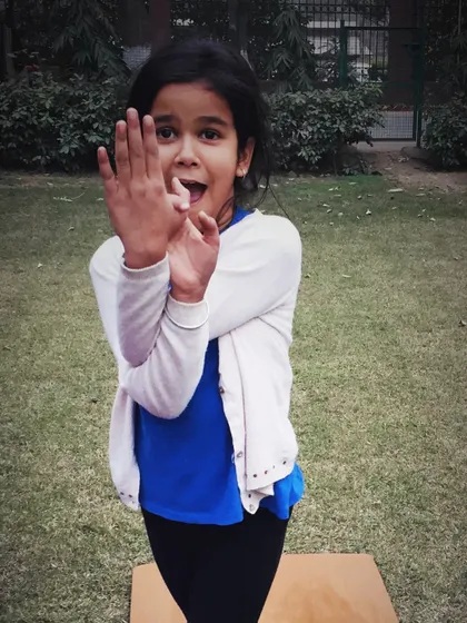 A young girl playfully practices Garudasana, the eagle pose, during our Christmas yoga day.