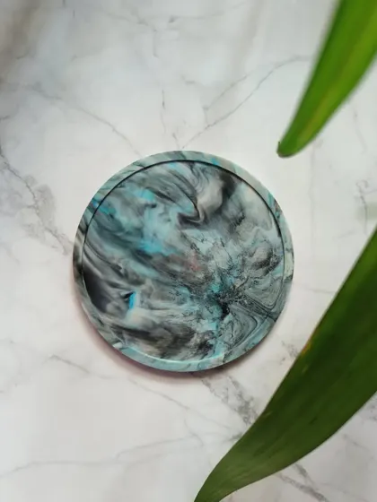 The turquoise and black swirls on this coaster are reminiscent of a stormy sea. It's a perfect example of how we turn waste into a thing of beauty.