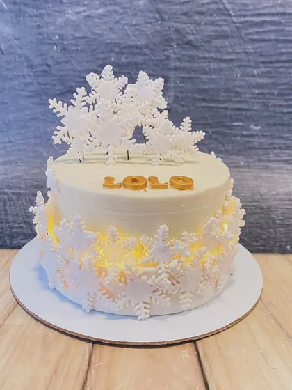 A stunning winter-themed cake that lights up from within. The design is adorned with intricate white snowflakes, creating a magical glowing effect.