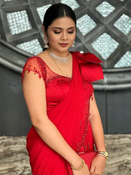 A close-up of the client, her expression serene and confident, highlighting the beautiful details of her red gown and sparkling jewellery.