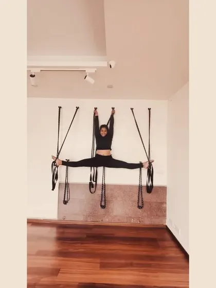 A wider view of the Samakonasana practice with wall ropes. This setup allows the practitioner to relax into the stretch, focusing on breath and release rather than straining to hold the position.