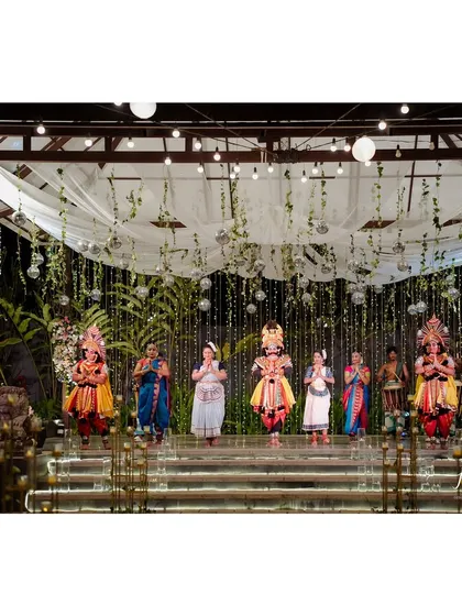 This Sangeet night has a disco vibe, with suspended disco balls, lush green creepers, and flowing drapes. The stage is set for a traditional dance performance, blending glam with culture.