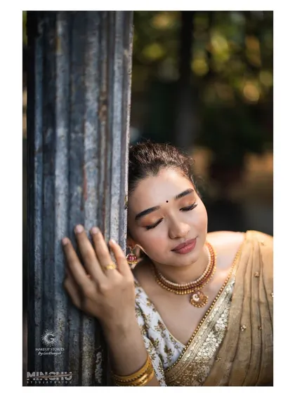 A serene portrait of Priyanka during her Varapooja function. The makeup is soft and natural, with a focus on flawless skin and a gentle, earthy eyeshadow look.