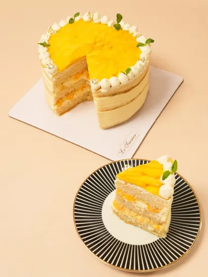 My Mango Vanilla cake, deconstructed. This shot shows the full cake alongside a perfect slice, revealing the generous layers of fresh mango and light vanilla cream.