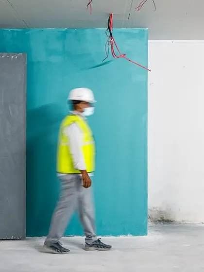 The hustle is real on site. This motion-blurred shot of an engineer walking through a partially painted space captures the constant movement and progress of a live project.