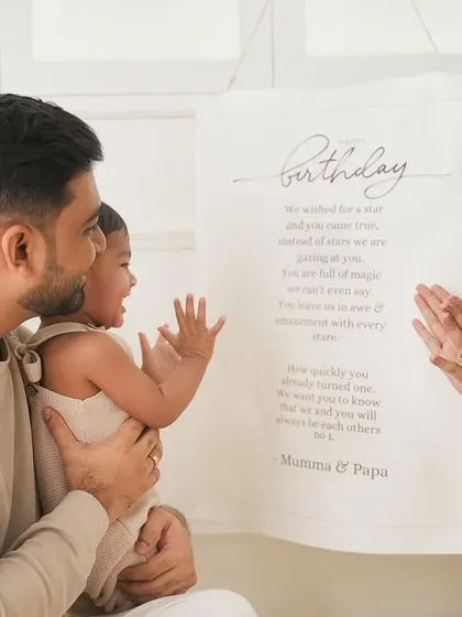 A family shares a beautiful, candid moment during a first birthday shoot, reading a personalized birthday message together.