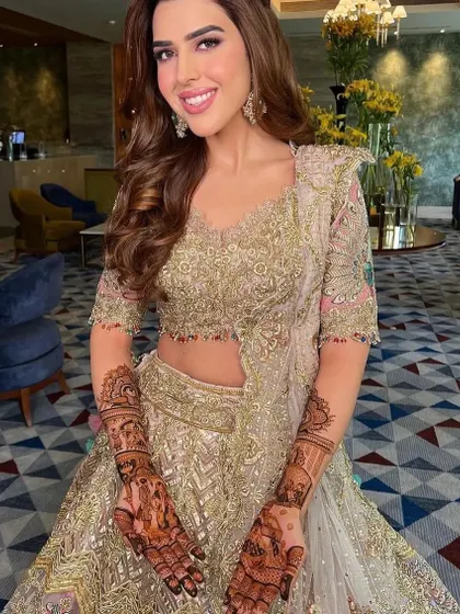 A beautiful bride in her wedding lehenga, proudly showing her detailed mehndi.