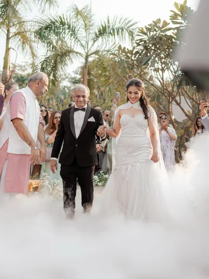 The bride walks down the aisle with her father, enveloped in a cloud of smoke for a dramatic and magical entrance. This is a powerful and emotional moment for any father and daughter.