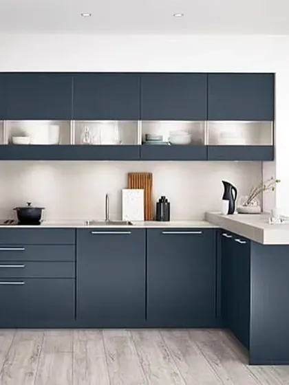 In this compact U-shaped kitchen, a small extension of the countertop creates a cozy breakfast nook for two. The deep blue cabinets and light wood-effect flooring give the space a modern, Scandinavian feel.