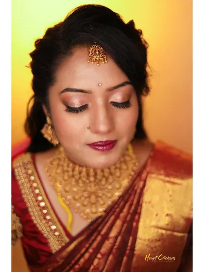 A close-up bridal portrait focusing on the flawless makeup and traditional gold jewelry.