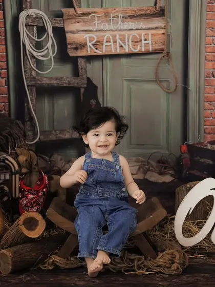 A happy cowboy in our rustic ranch setup. This first birthday shoot combines a fun theme with a classic milestone celebration.