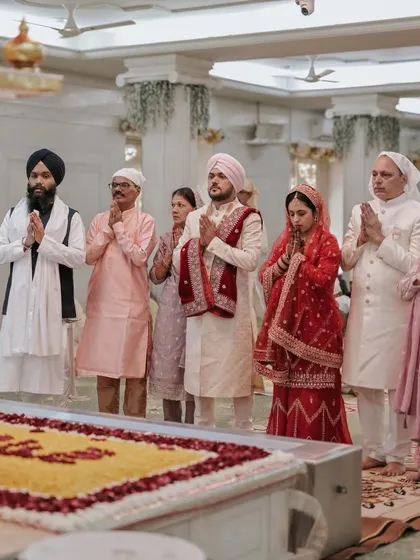The couple and their family stand in prayer, a poignant moment of unity and blessings during the Sikh wedding.