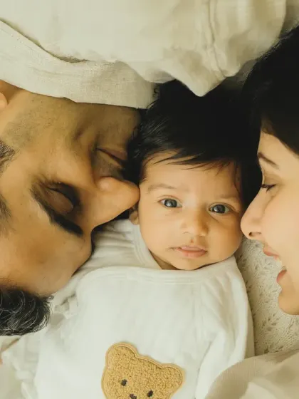 An intimate overhead shot of new parents admiring their baby. This perspective creates a feeling of being right there in that loving moment.