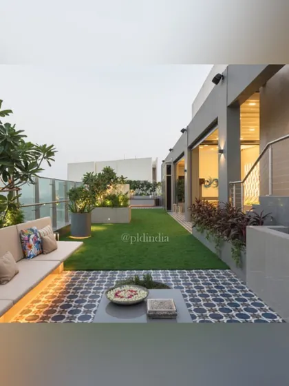 This view shows the different textures used in the terrace design, from the patterned tiles of the seating area to the soft artificial grass and the lush foliage in the planters.