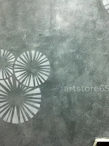 A detailed look at the sunburst-style stencil used for a modern bedroom wall. The clean lines of the silver pattern stand out against the subtle, hand-applied dark grey texture.