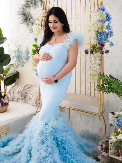 Standing tall and proud, this mother-to-be cradles her bump in a stunning light blue mermaid gown. The soft ruffles at the bottom add a touch of whimsy to this elegant maternity portrait.
