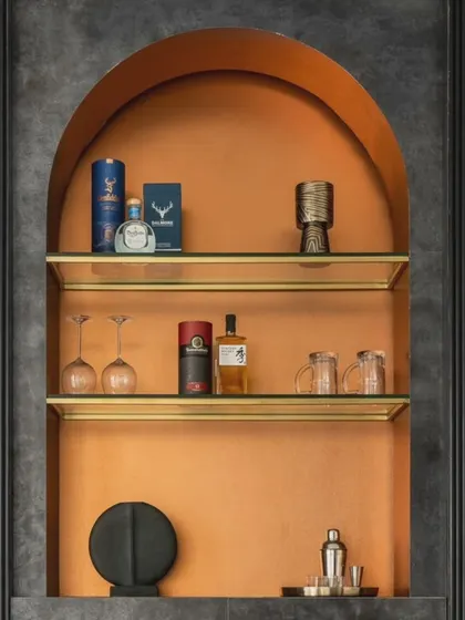 Detail of the custom bar cabinet in Dr. Harsha's home. The arched niche, finished in a bold orange, provides a vibrant backdrop for displaying glassware and spirits.