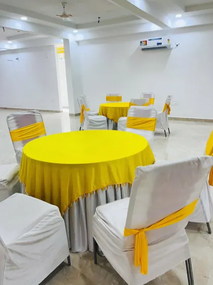 Simple and clean guest seating for a Haldi function. I provided round tables with yellow tablecloths and chairs with white covers and matching yellow sashes.