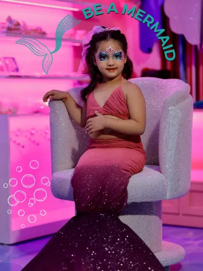 Live the mermaid dream with our glittery face paint and a beautiful, shimmering tail. This photo captures the enchanting final look of our 'Mermaids of Wooray' transformation.