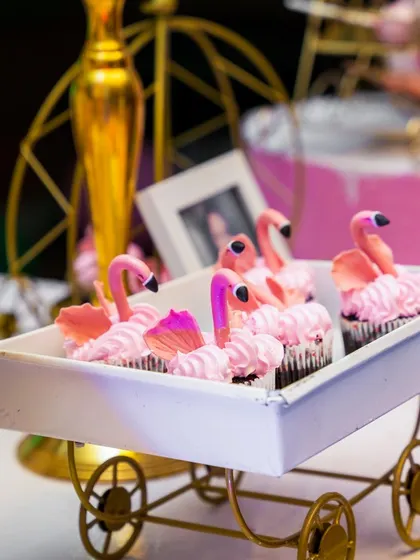 Adorable flamingo-topped cupcakes displayed in a miniature cart. Even the desserts are part of the decor, adding to the charm and theme of the party.