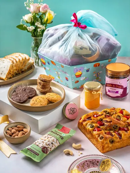 A large, beautifully wrapped gift hamper from Drizzle & Dust, filled with baked goods and snacks.