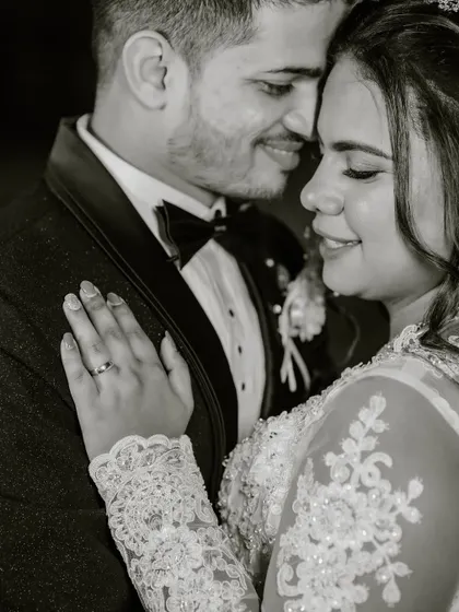 A close-up, black and white shot capturing a tender moment. You can see the delicate lace of her sleeve and the soft glow of her makeup even in monochrome.