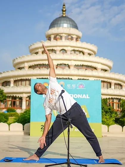An instructor demonstrates Trikonasana (Triangle Pose) during an International Day of Yoga event. Our yoga sessions are guided by experienced teachers who ensure proper alignment and help you get the most out of each posture.