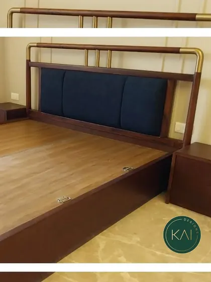 A custom bed frame made from rich, dark wood with a contrasting navy blue upholstered panel in the headboard. The brass-finished metal railing adds a touch of classic elegance to this sturdy and stylish piece.