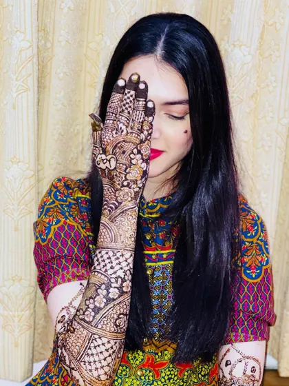 A beautiful shot of the bride with her eyes closed, highlighting her stunning makeup and the intricate henna on her hand.