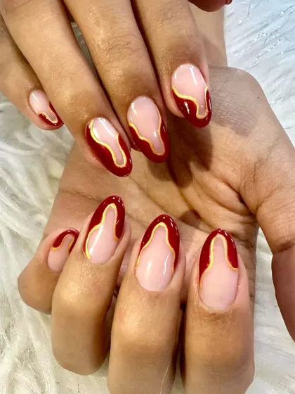 Soft glam with a bold heartbeat. This design features a deep red abstract shape outlined in gold on a sheer nude base, creating a modern and artistic look.
