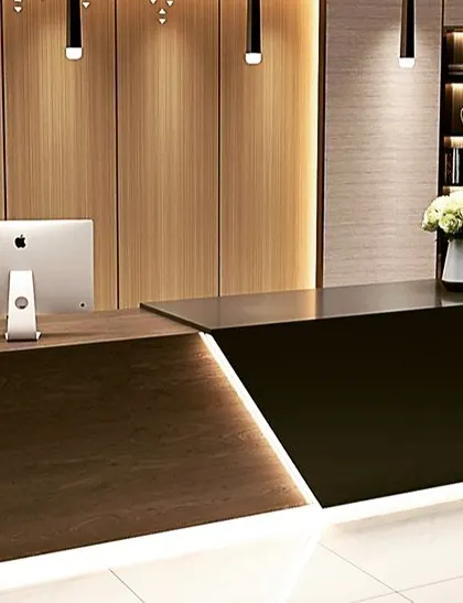 A sleek, two-tone reception desk in dark wood and black, with integrated LED lighting creating a sharp, modern look. This design is ideal for a contemporary corporate office or studio.
