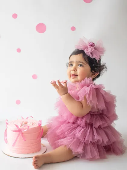 A first birthday is a huge milestone, and a cake smash is the perfect way to celebrate. This little one is having the best time with her very own pink cake in a clean, minimalist setup.