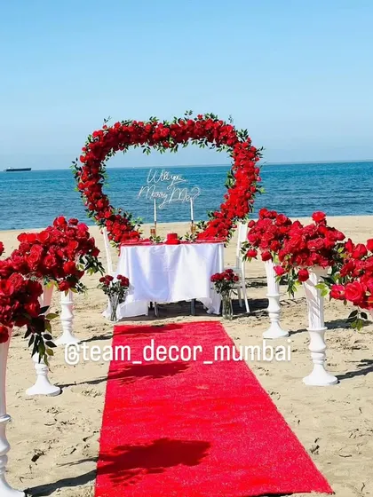 This shot captures the complete beach proposal scene, showcasing the stunning contrast of the red roses and carpet against the blue sky and sea. I can set this up at various beach locations around Mumbai.