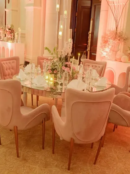 The dining setup for the ring ceremony featured elegant blush pink chairs around a mirrored table, with tall candelabras and floral centerpieces creating a sophisticated and intimate atmosphere.