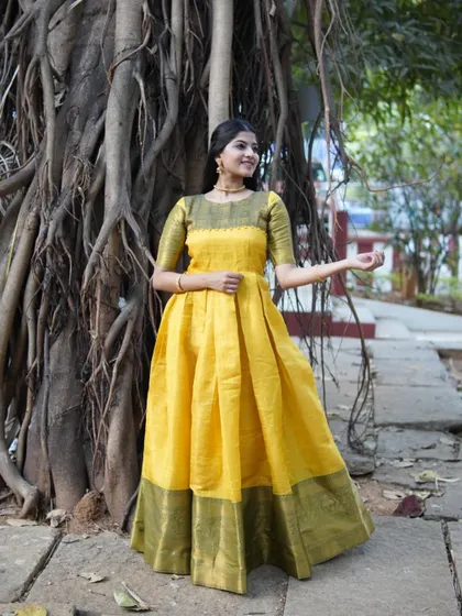 A bright and cheerful yellow long gown with a green border. The outdoor setting and the full flare of the gown create a picture of happiness and celebration.