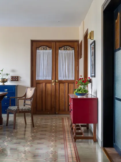 Another view of the Calcutta home, showing the warm wooden doors and a pop of red from a side console. The design is layered with color and texture, creating a home that feels vibrant and full of life.