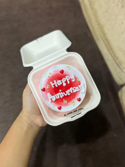 A cute and trendy bento box anniversary cake with red frosting and gold leaf.