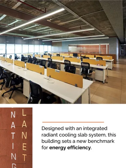 The open-plan office at Mahindra Chakan is designed with an integrated radiant cooling slab system, a benchmark for energy efficiency. The raw concrete ceiling and industrial aesthetic are balanced by views of the surrounding landscape.