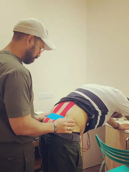 Final adjustments are made to the kinesio tape application on a client's lower back. Our attention to detail ensures the taping is effective for providing support and pain relief.