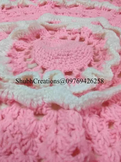 A close-up of a pink and white crochet piece, showing the detailed stitch work and layered construction.