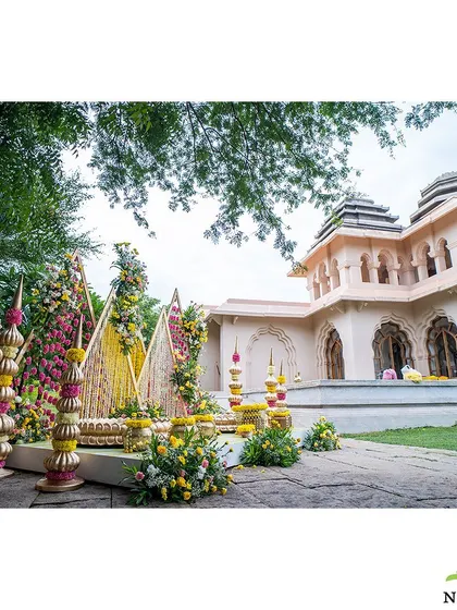 The pastel Mangalasnanam setup seen in context with the venue's architecture. The modern, geometric design of the decor creates a beautiful contrast with the traditional building.