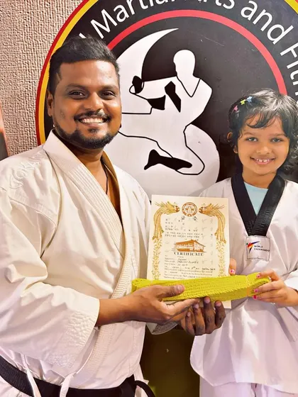 A happy student receives her yellow belt, celebrating the first of many achievements in her martial arts journey.