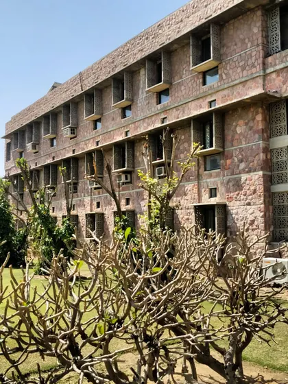 The building's facade showing deep-set windows and chajjas (shades). These passive design features are crucial in Rajasthan's climate, as they protect the interiors from harsh sun while allowing for natural ventilation.