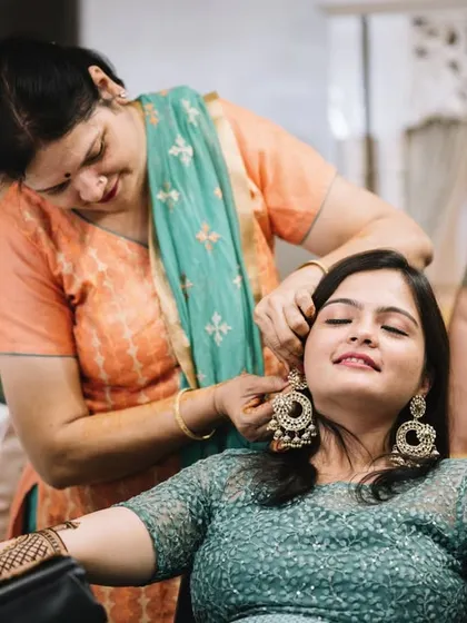 A friend helps Disha with her heavy earrings while the mehendi artist works. It’s a moment of care and friendship.