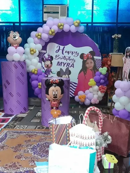 A cute Minnie Mouse theme for Myra's birthday. This setup includes a custom backdrop with her photo, balloon columns, and Minnie character cutouts.